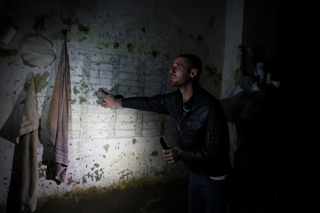 A former Syrian detainee points to a wall inside a prison cell where he was detained in Damascus on December 13, 2024.
