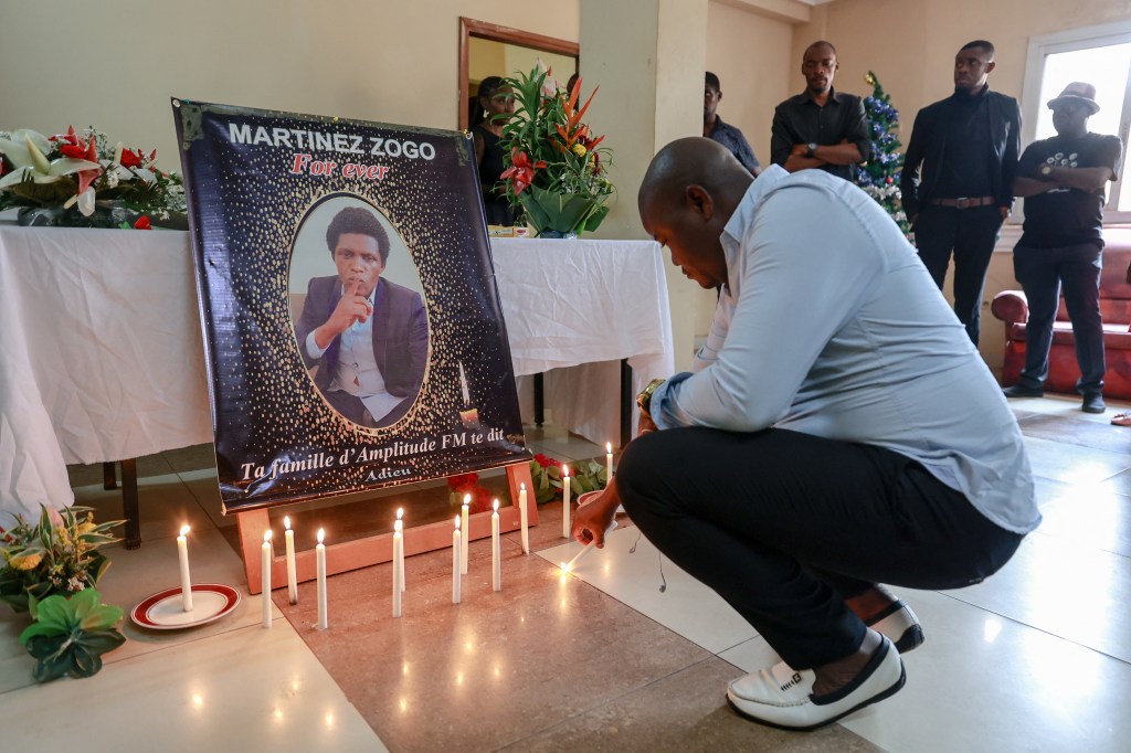 A mourner places a candle in a room of Radio Amplitude FM where a portrait of popular radio host Martinez Zogo has been placed to pay tribute to him, in Yaounde on January 23, 2023, the day after he was found dead.