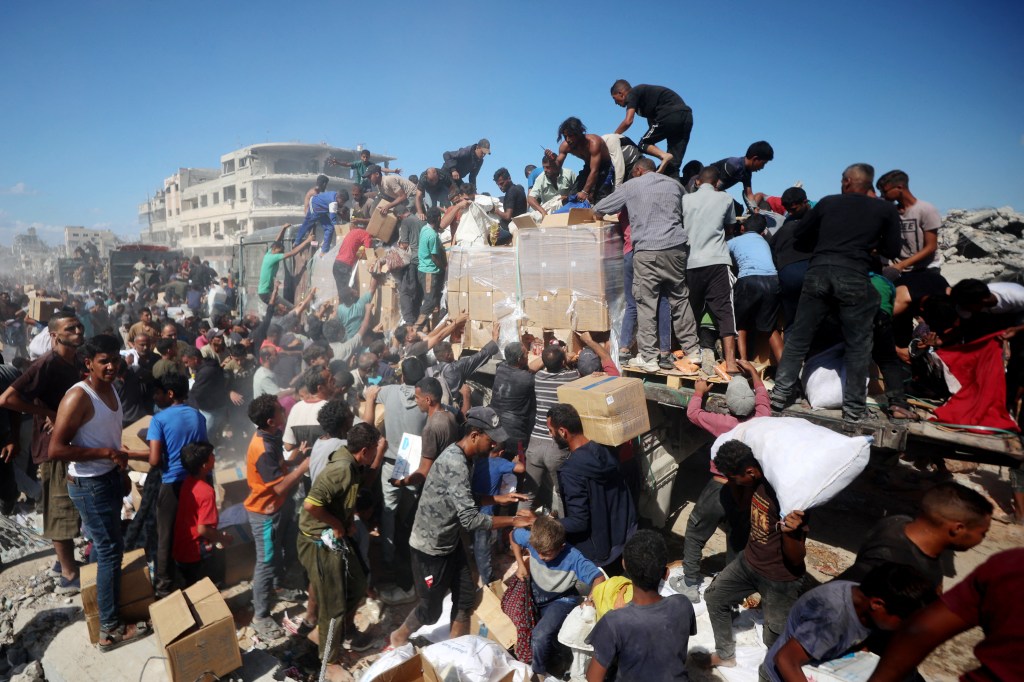 Palestinians collect aid parcels from aid trucks in the southern Gaza Strip on October 12, 2025.