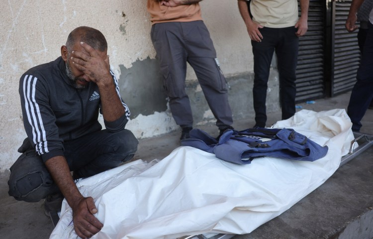 A man mourns over the body of Palestinian media worker Ahmed Abu Mutair, killed in an Israeli strike in the town of Zuwaida in the central Gaza Strip on October 19, 2025., nine days after a ceasefire agreement took effect. (Photo: AFP/Bashar Taleb)