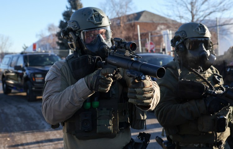 Members of law enforcement hold weapons as they stand guard while people protest outside the Bishop Henry Whipple Federal Building, after the fatal shootings of Renee Nicole Good and Alex Pretti by federal immigration agents, in Minneapolis, Minnesota, U.S., January 30, 2026. REUTERS/Shannon Stapleton