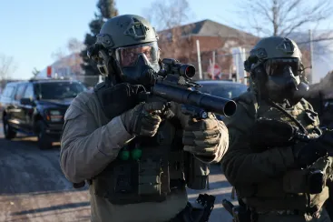 Members of law enforcement hold weapons as they stand guard while people protest outside the Bishop Henry Whipple Federal Building, after the fatal shootings of Renee Nicole Good and Alex Pretti by federal immigration agents, in Minneapolis, Minnesota, U.S., January 30, 2026. REUTERS/Shannon Stapleton