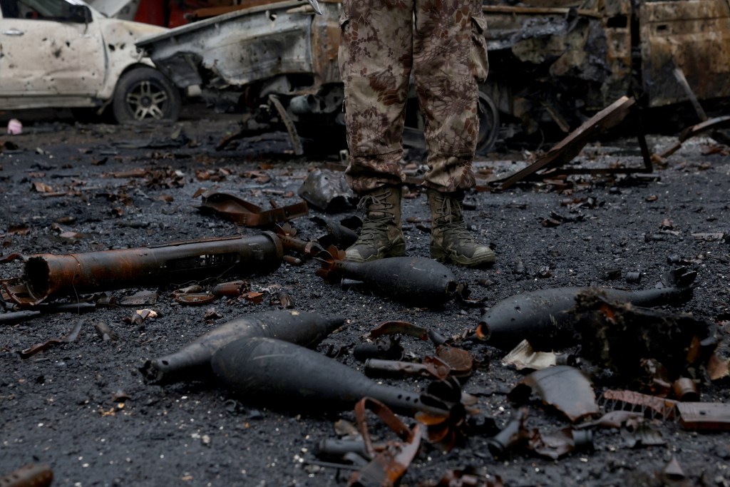 A Syrian security officer stands next to munition strewn on the ground following a ceasefire which ended several days of fighting between Syrian security forces and Kurdish fighters in the Kurdish-majority Sheikh Maqsud neighbourhood of Aleppo.