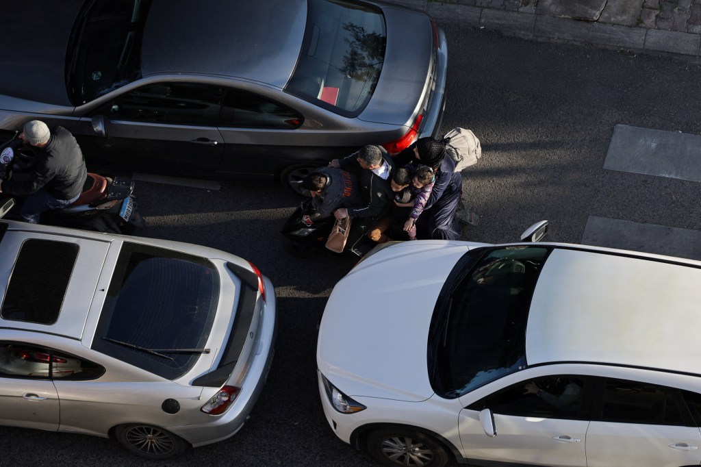 People with children on a scooter weave between cars, as Beirut traffic surges after Israeli army warning prompts residents to evacuate the city's southern suburbs amid the Iran war.