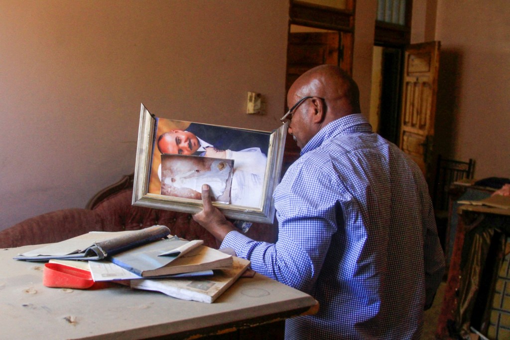 AFP journalist Abdelmoneim Abu Idris Ali holds his wedding picture as he searches through documents at his home in Khartoum North's Bahri neighbourhood on March 17, 2025, as he returns to visit for the first time since being displaced.