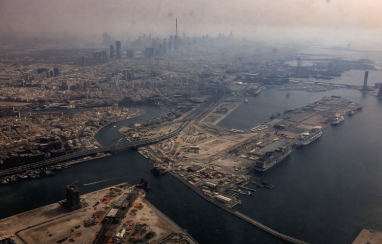 A view from inside a stained window of an airplane shows Dubai International Airport, with the Burj Khalifa in the background, on March 8, 2026, amid the Iran war.