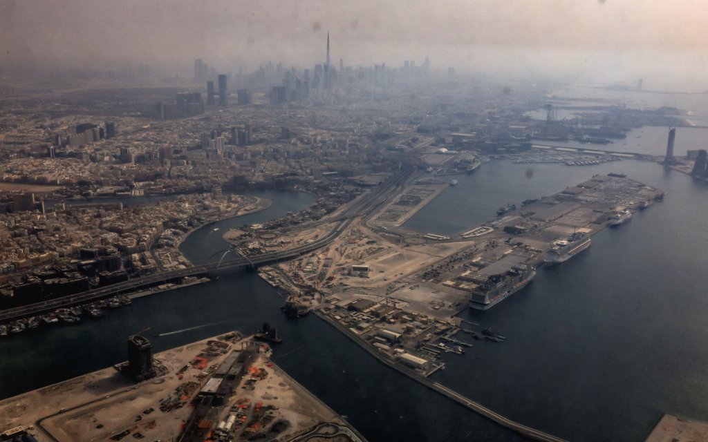 A view from inside a stained window of an airplane shows Dubai International Airport, with the Burj Khalifa in the background, on March 8, 2026, amid the Iran war.