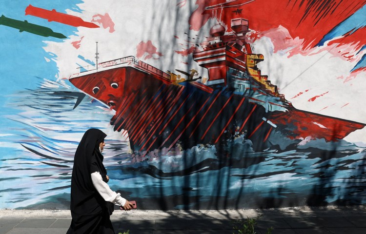 A woman walks next to a mural on a street in Tehran, Iran, May 18, 2026.