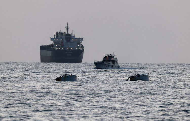 Israeli soldiers are seen on a vessel bearing symbols of the Global Sumud Flotilla, with a cargo ship behind it, as seen from Ashdod, southern Israel, on May 19, 2026.