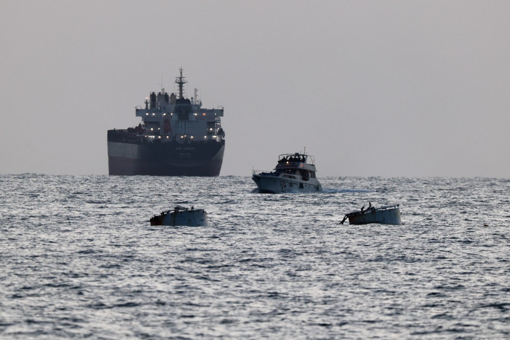 Israeli soldiers are seen on a vessel bearing symbols of the Global Sumud Flotilla, with a cargo ship behind it, as seen from Ashdod, southern Israel, on May 19, 2026.