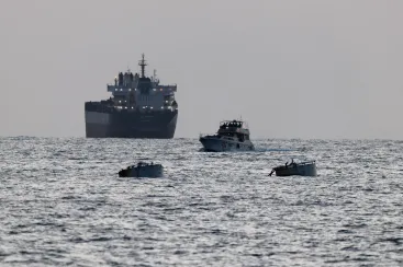 Israeli soldiers are seen on a vessel bearing symbols of the Global Sumud Flotilla, with a cargo ship behind it, as seen from Ashdod, southern Israel, on May 19, 2026.