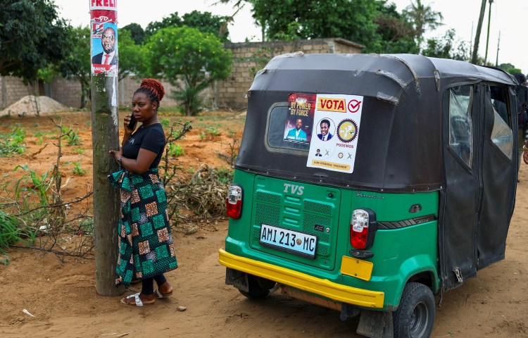 A woman speaks on a phone next to election posters, ahead of the announcement of the results of October 2024's election in the capital, Maputo.