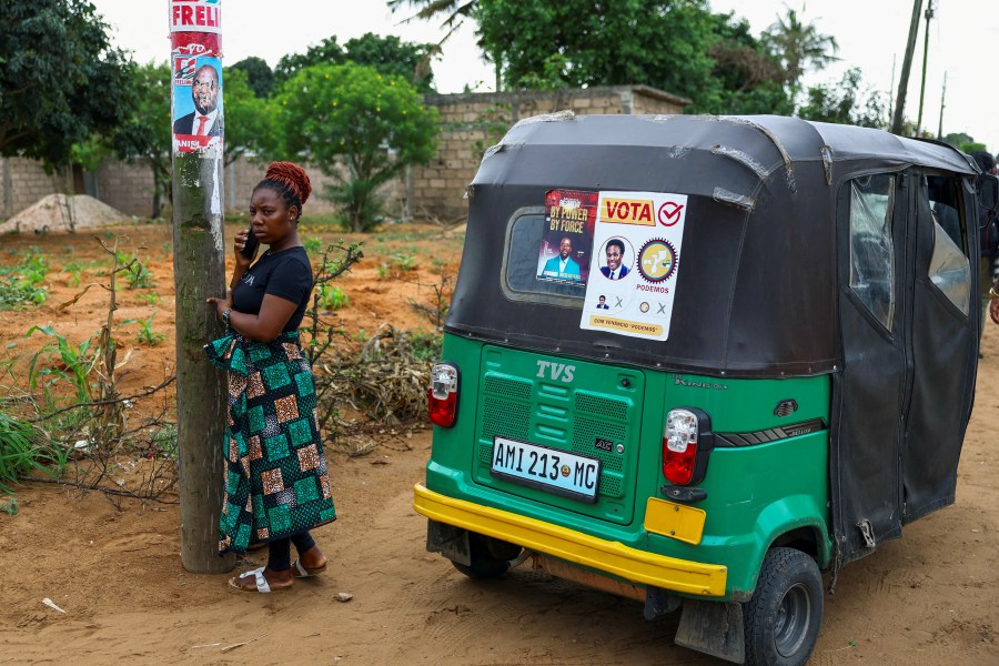 A woman speaks on a phone next to election posters, ahead of the announcement of the results of October 2024's election in the capital, Maputo.