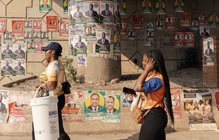 Women walk past electoral campaign posters in Lusaka, on August 9.