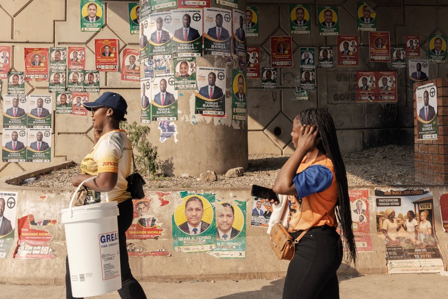 Women walk past electoral campaign posters in Lusaka, on August 9.