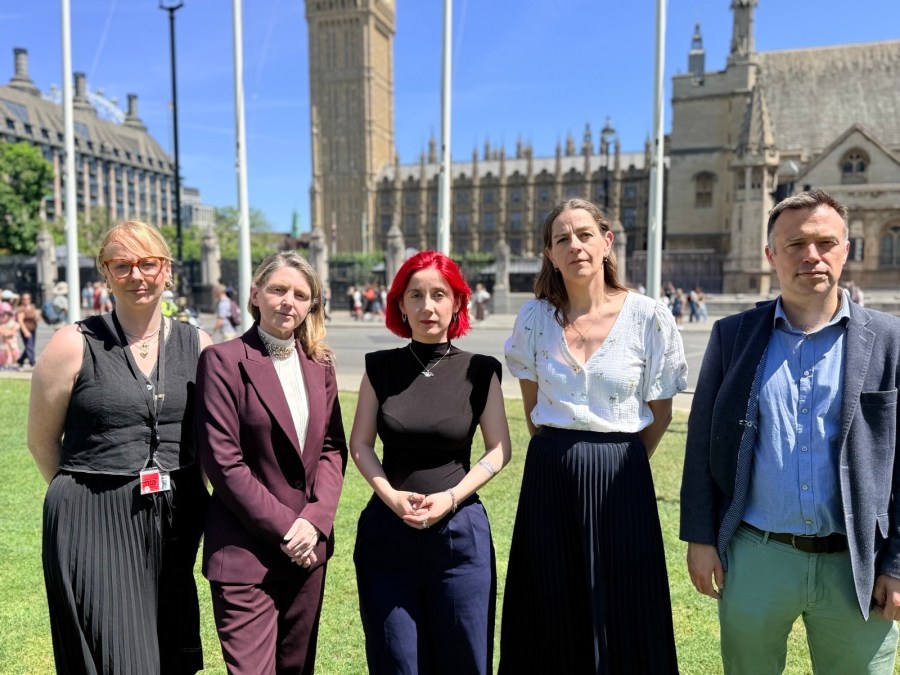 Five people stand outside, posing for the camera in a line.